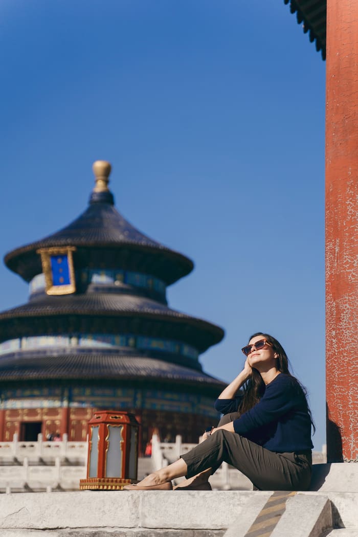 Una turista sentada contempla el histórico Templo del Cielo en Beijing, China. Fotografía de viaje en beijing-con arquitectura imperial de fondo
